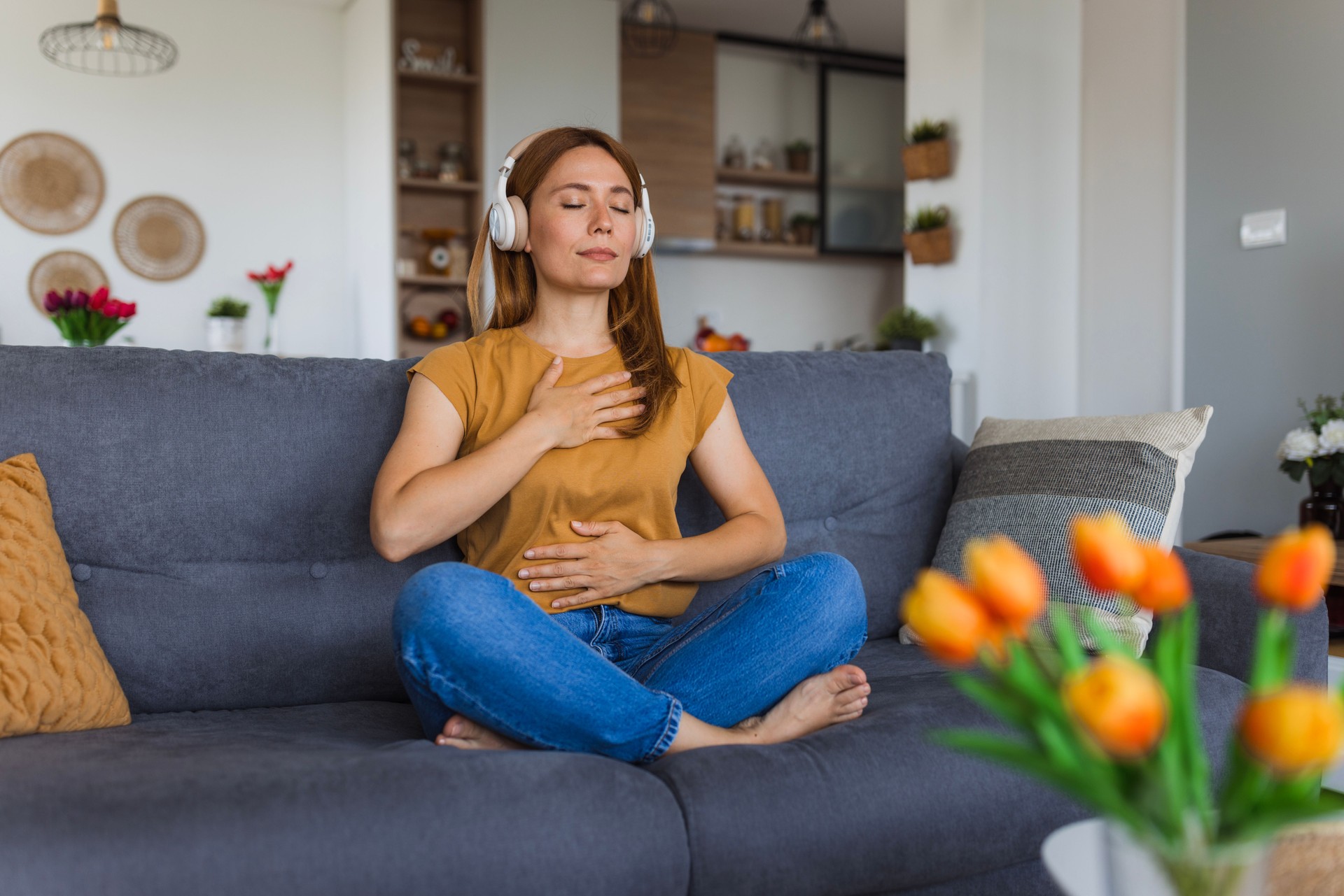 Serene woman practicing mindfulness with music on sofa at home